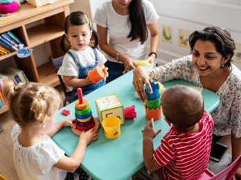 Nursery children playing with teacher in the classroom